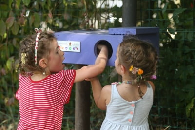 Deux petites filles explorent une boîte sensorielle, plongeant leurs mains pour découvrir des textures mystérieuses et stimulantes.